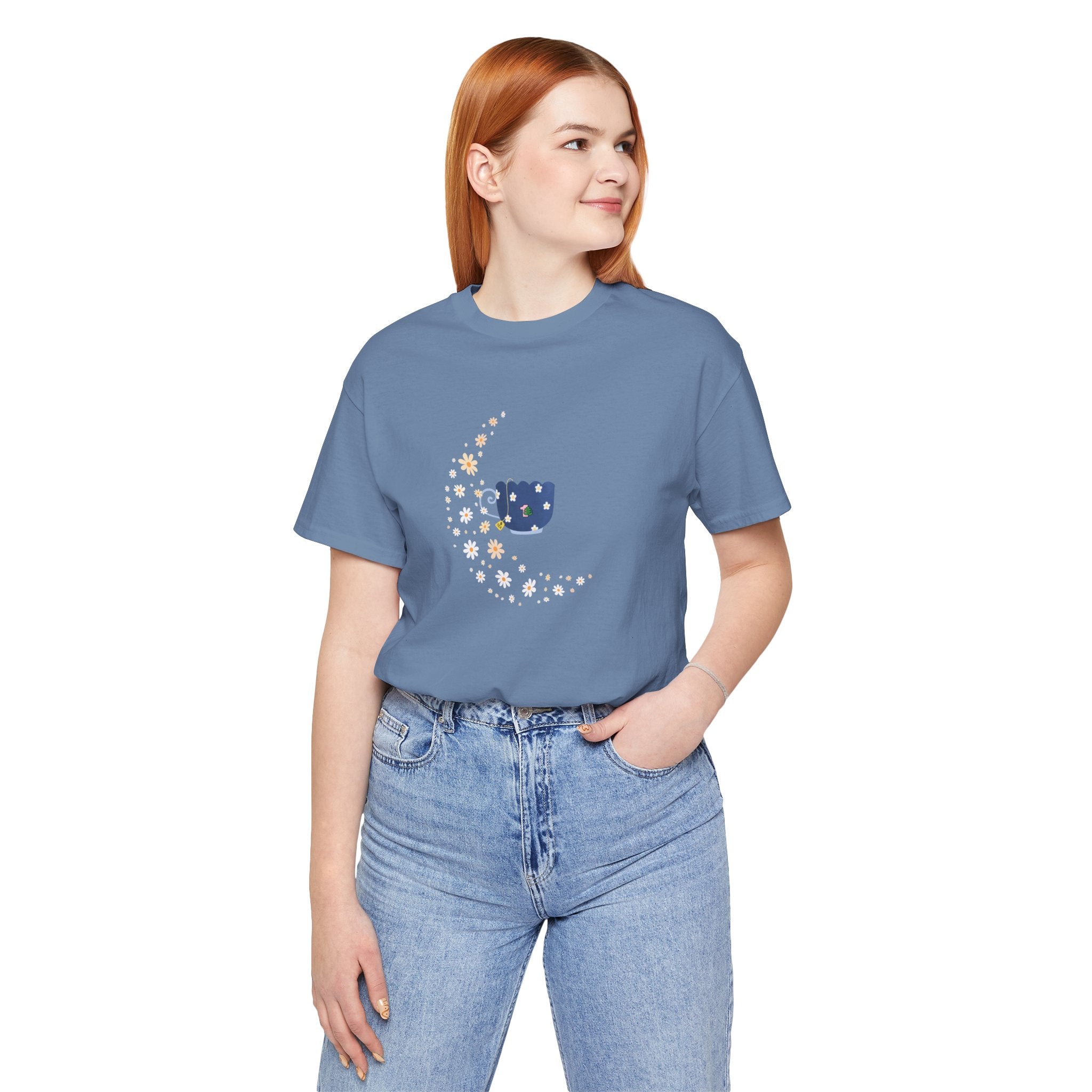 A student wearing a steel blue colored shirt featuring a floral moon and a teacup design.  The top has a crew neck and short sleeves.  