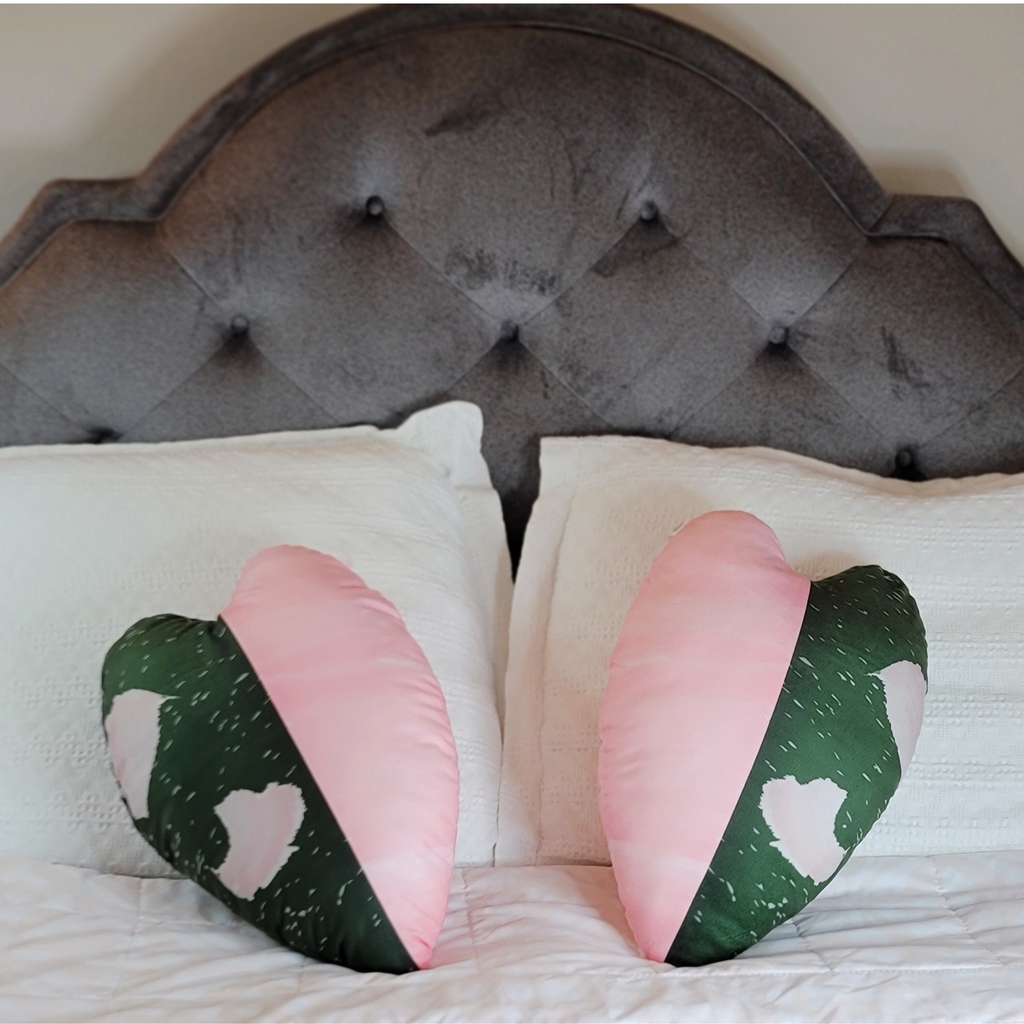 philodendron plant pillow as a heart-shaped cushions on a bed with a tufted headboard