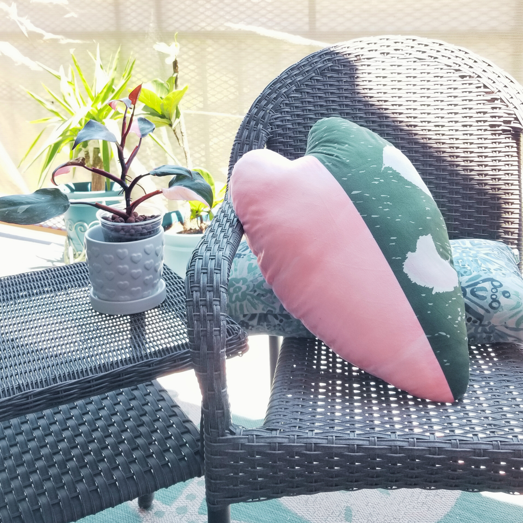 Wicker chair with pink and green tropical cushions on a patio setting