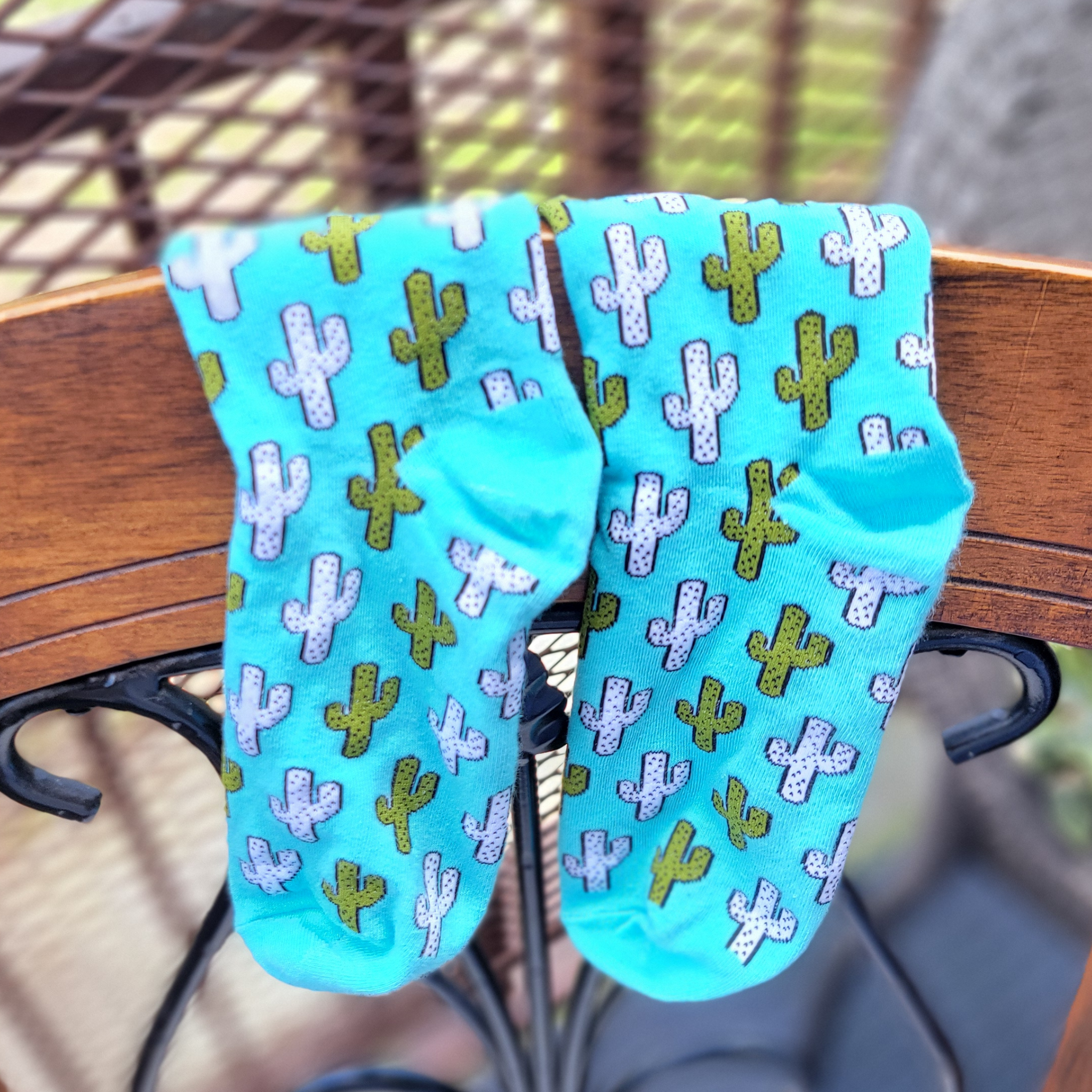 Turquoise socks with cactus pattern hanging on a chair