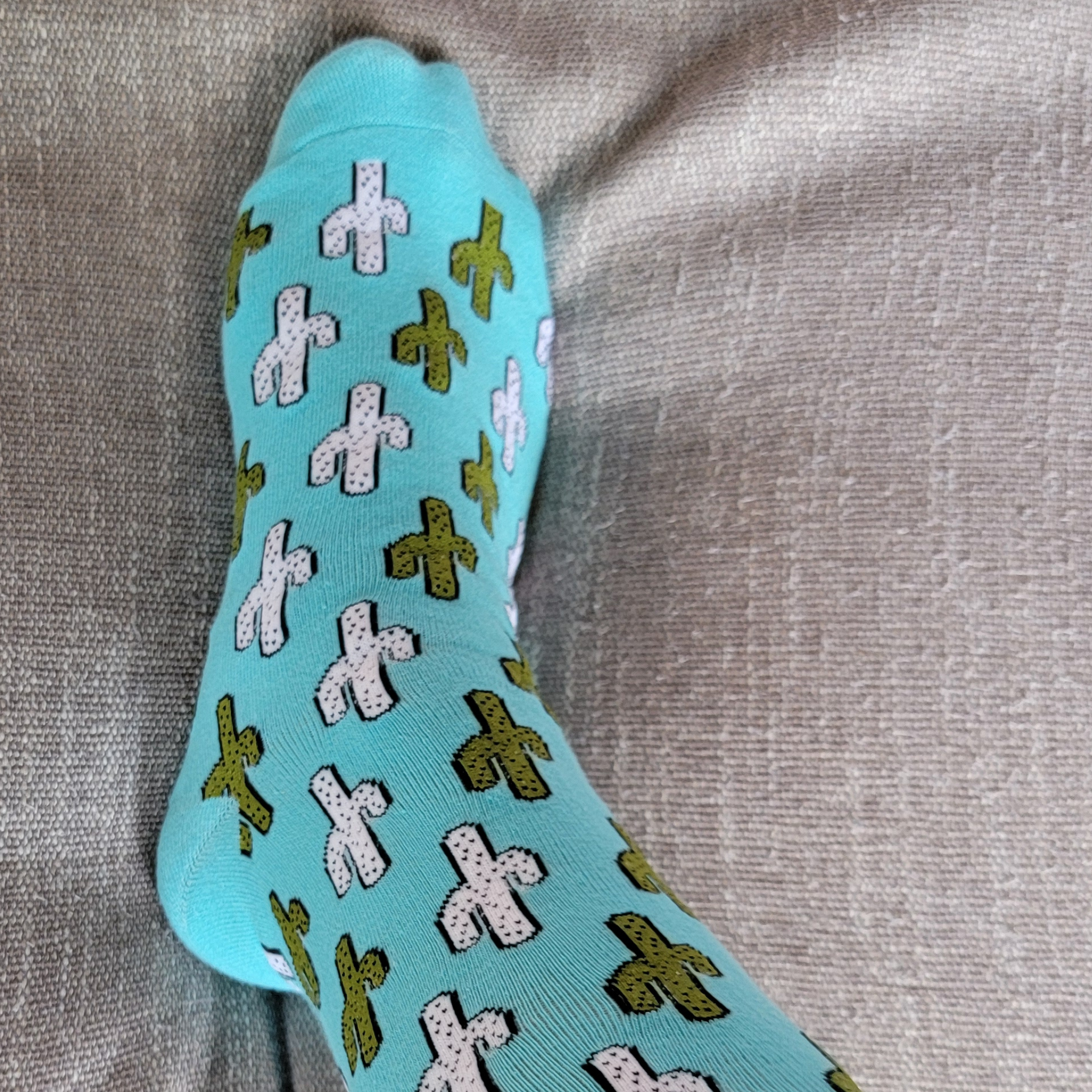 Blue sock with white and green patterns on a gray fabric background