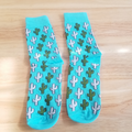 A pair of blue socks with a cactus pattern in white and green.